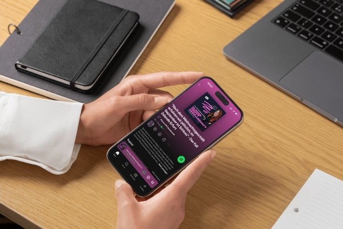 Person hält Smartphone mit Podcast-Folge auf dem Bildschirm.